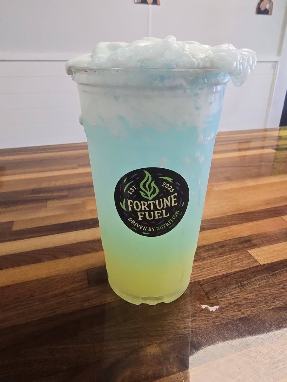A tall layered blue energy tea in a Fortune Fuel cup