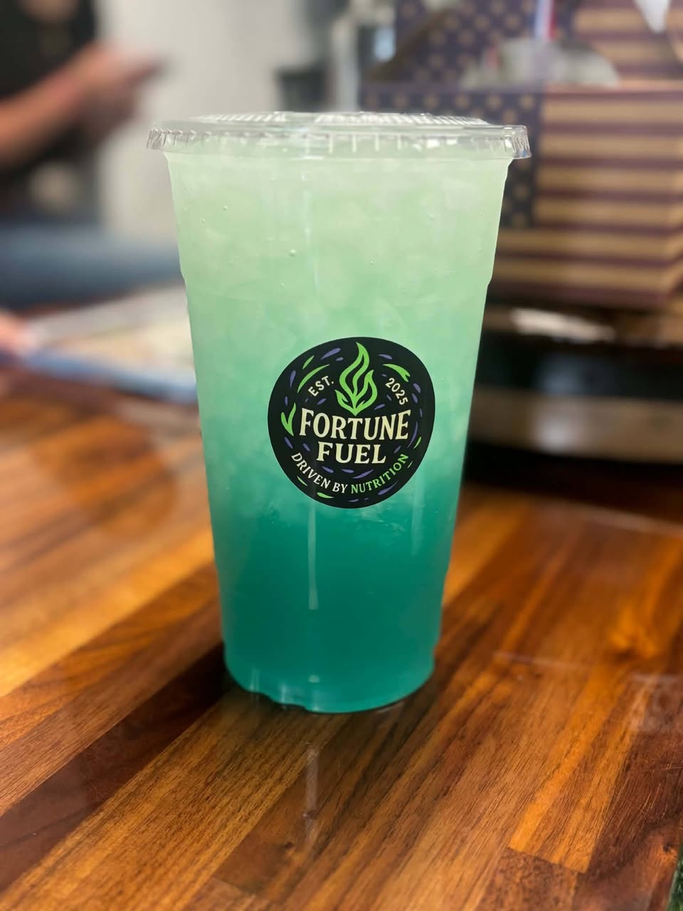 A single teal layered energy tea on a wood table