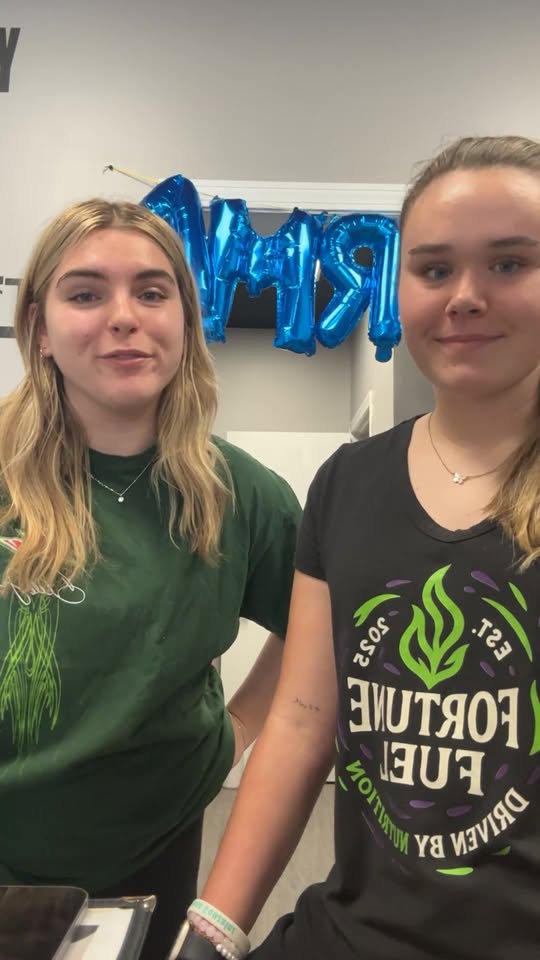 Two Fortune Fuel team members smiling behind the counter in branded tees