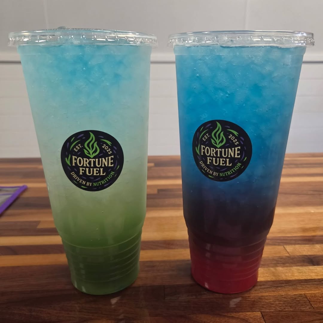 Two layered teas in blue and green, side by side on a wood table